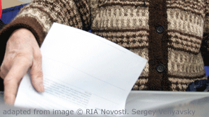 Image of Person in Brown Sweater Placing Paper into Box