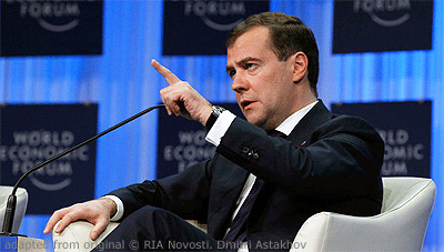 File Photo of Dmitri Medvedev Seated and Gesturing with World Economic Forum Banners in the Background