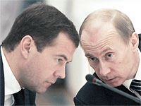 File Photo of Dmitry Medvedev and Vladimir Putin, With Heads Bowed Over Microphone