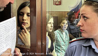Pussy Riot Defendants in Courtroom Enclosure, with Man Showing One Papers through Glass While Female Guard Looks On