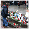 Little Boy Placing Flowers Before Photos of Victims of Terrorism